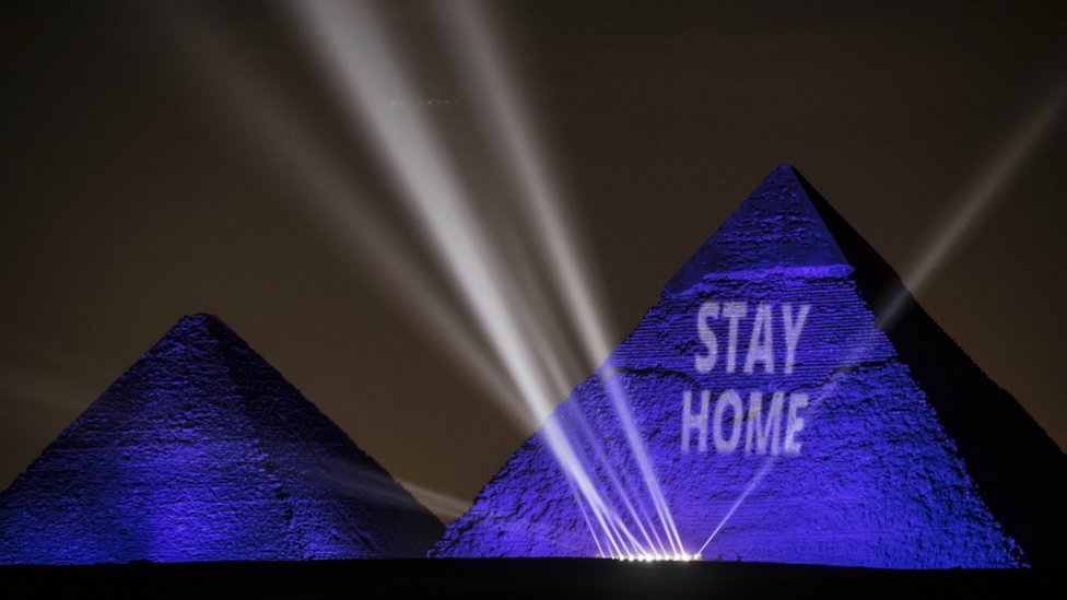 The pyramids are illuminated in blue with the message "stay home" in white lettering.