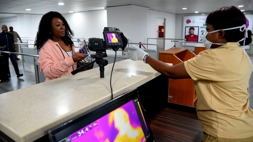 One Port Health Service staff member stands next to one thermal scanner as passengers dey arrive for di Murtala Mohammed International Airport for Lagos,