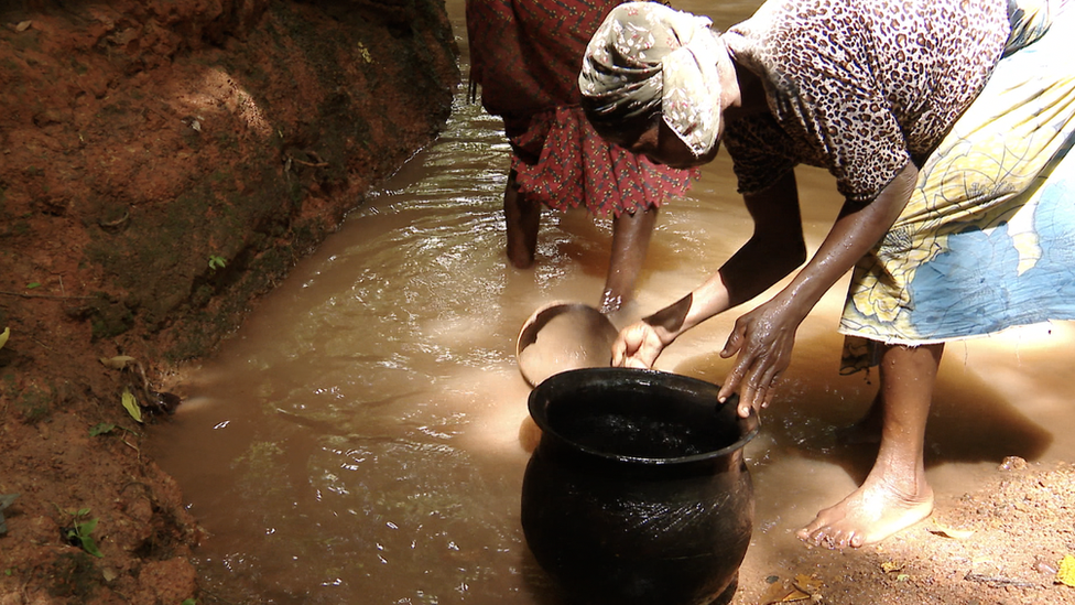 Woman dey fetch water for stream