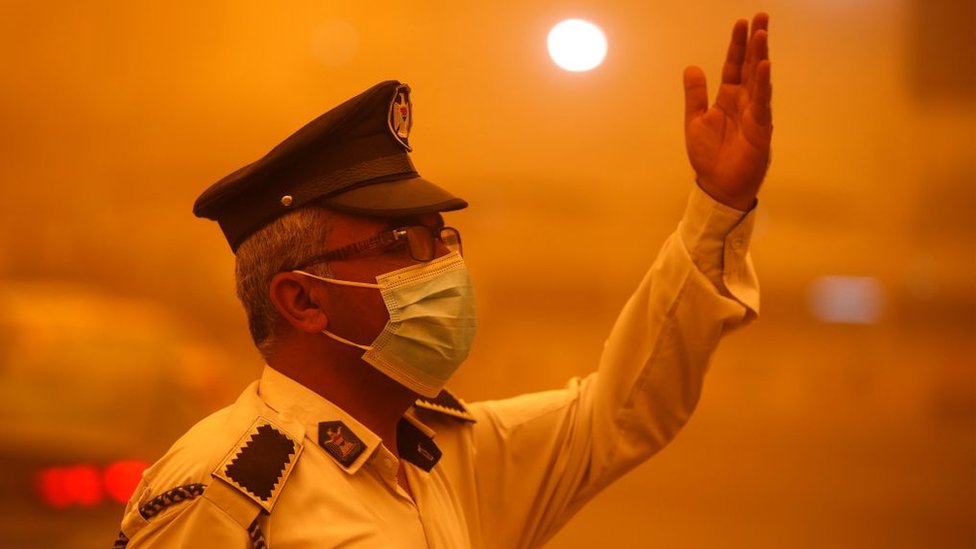 An Iraqi policeman directs traffic during one severe dust storm forn the capital Baghdad
