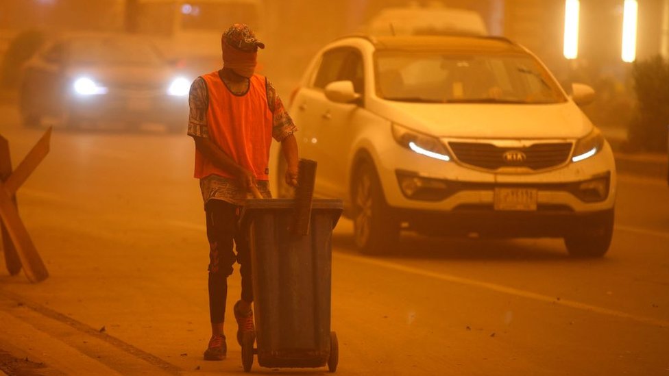An Iraqi cleaner works to clean the street during a severe dust storm in the Iraqi capital Baghdad