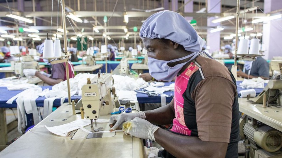 Man dey use sewing machine take make personal protective equipment for Covid-19 frontline health workers for one factory goment commission for Accra. (April 17, 2020)