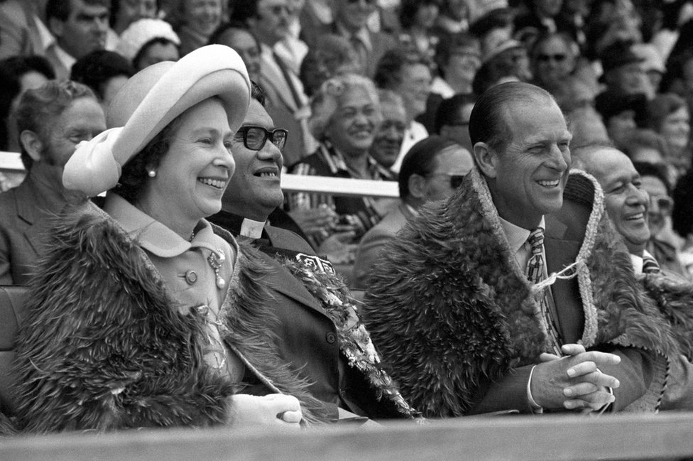 Di Queen and di Duke of Edinburgh, both of dem wear di Maori Kahu-Kiwi (Kiwi feather cloaks) for Rugby Park in Gisborne, for di North Island of New Zealand wen dem attend di opening of di Royal New Zealand Polynesian Festival as their Silver Jubilee Tour continue