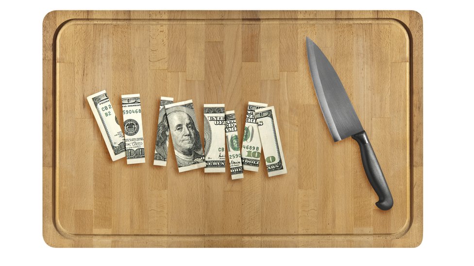 A chopping board with a hundred dollar bill cut into pieces