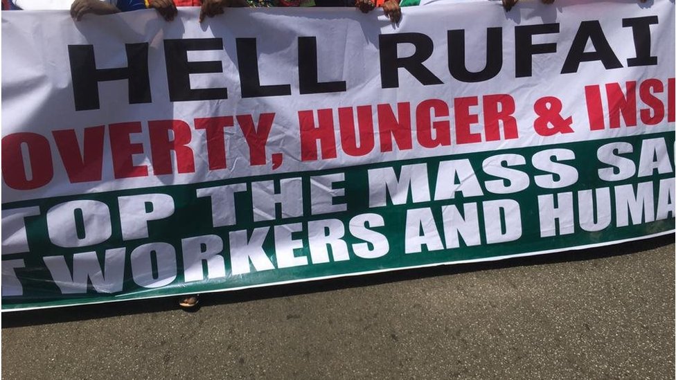 Banner wey some of di workers carry on di first day of di strike