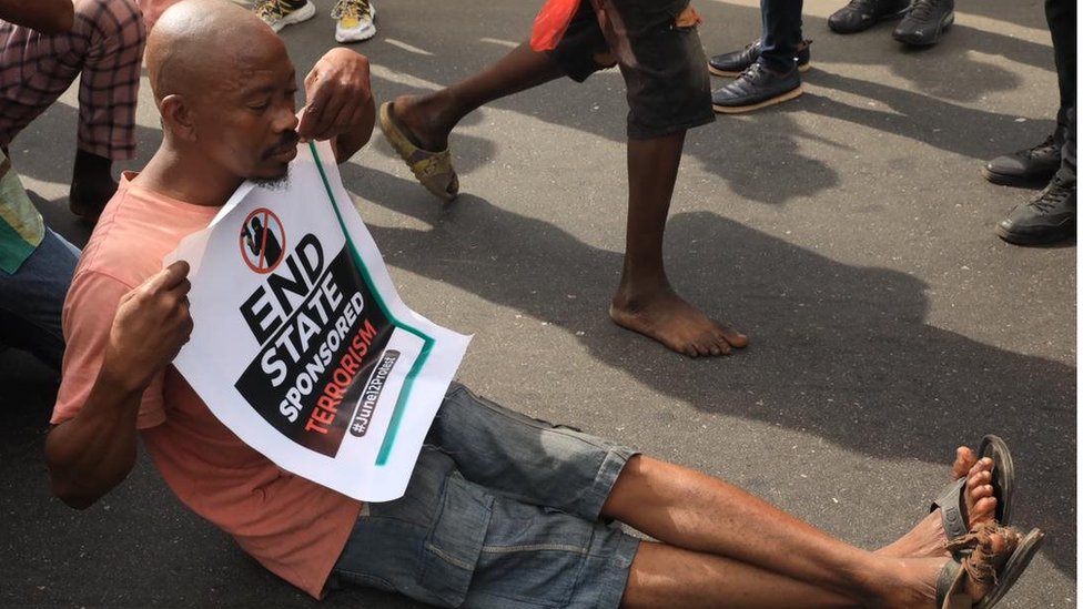 Man siddon for ground with placard for Ojota, protest venue on June 12, 2021