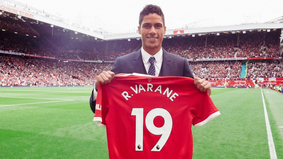 Raphael Varane pose on di pitch wit e Manchester United shirt, wey carry number 19