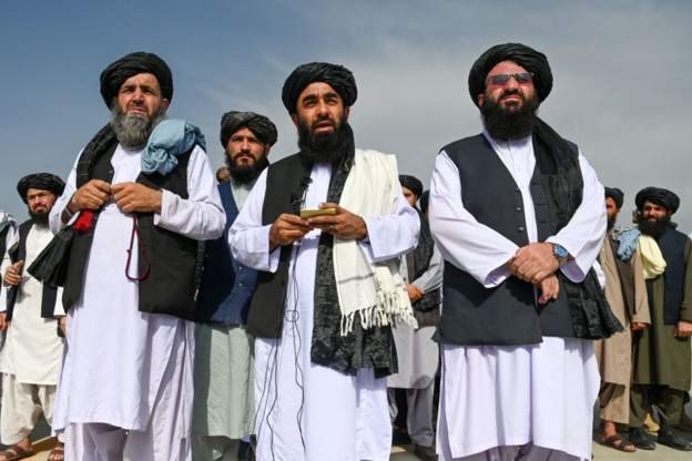 Taliban spokesman Zabihullah Mujahid (centre) dey speak to di media