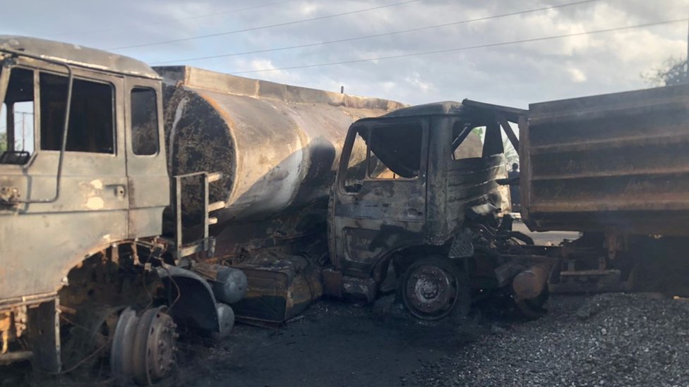 Di burnt remains of di trucks wey dey involved for di collision