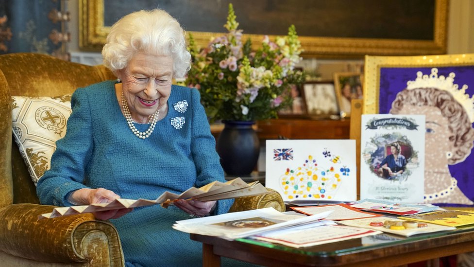 The Queen looks at a fan, surrounded by memorabilia from her jubilees