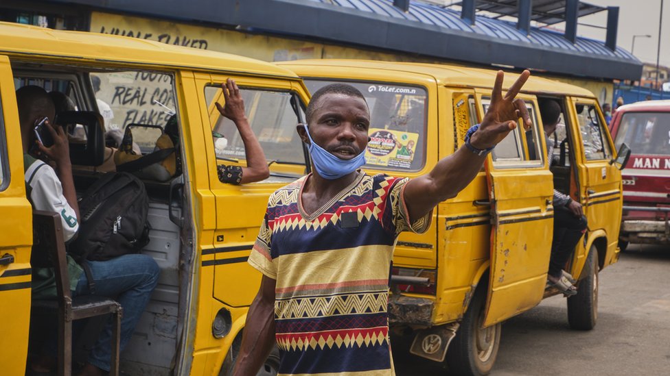 Conductor stand in front of a Lagos danfo