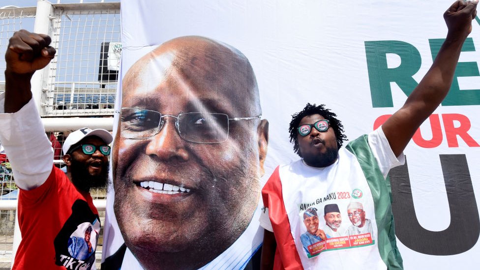 Supporters dey next to di banner of di candidate of di opposition Peoples Democratic Party (PDP) Atiku Abubakar during campaign rally for Kano, Nigeria - 9 February 2023