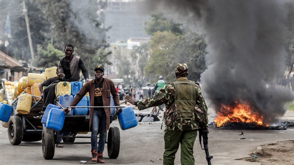 One Kenyan Police officer stop some workers for road wey dem close during demonstrations in Nairobi, Kenya on July 12, 2023