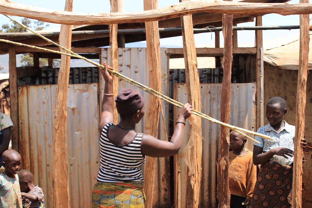 Woman and her children dey build house for di camp