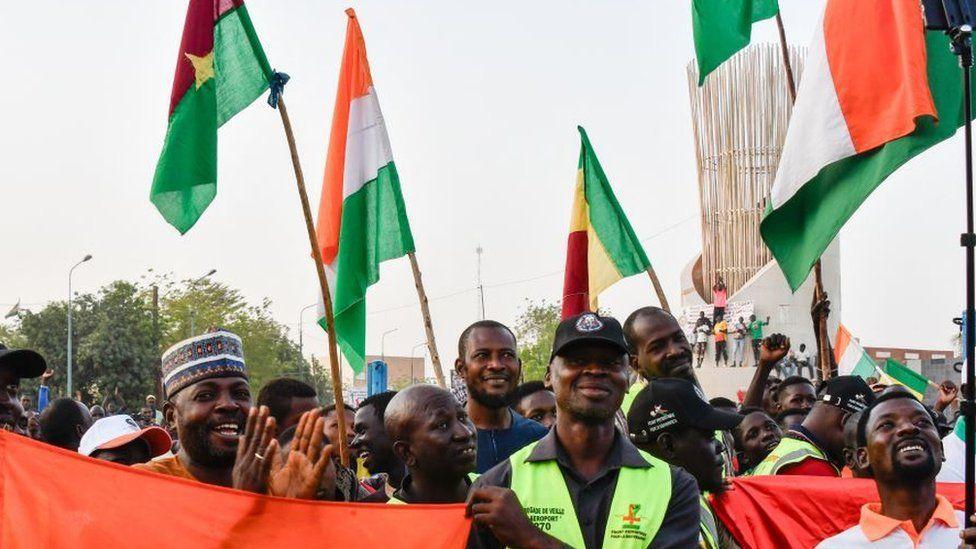 Supporters of di Alliance of Sahel States hold flags to celebrate as Mali, Niger and Burkina Faso comot Ecowas 