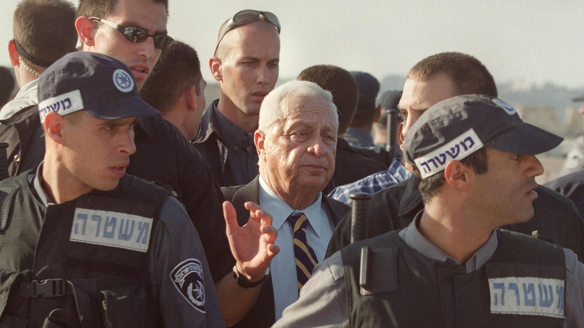 Di den Israeli Prime Minister Sharon wey guards surround am as e dey leave al-Aqsa mosque in 2000