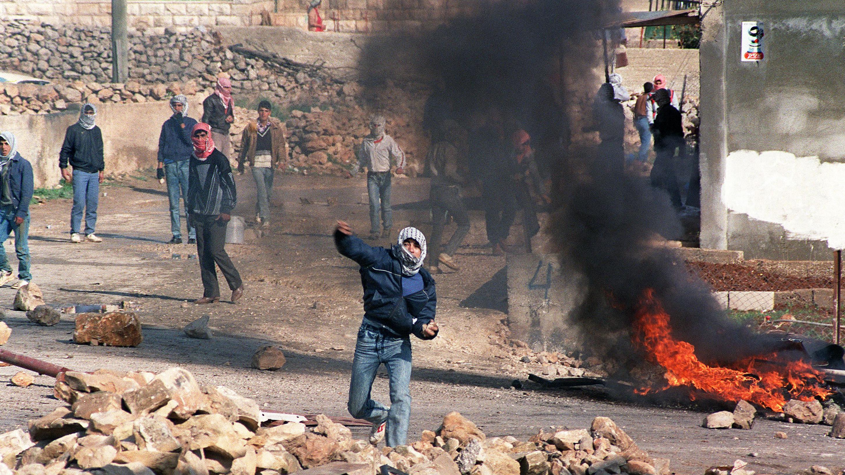 Rioters throw stones alongside burning material