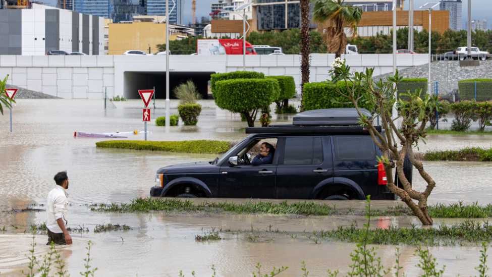 Driver dey wait as e dey try drive for flooded road for di Dubai Sports City district of Dubai