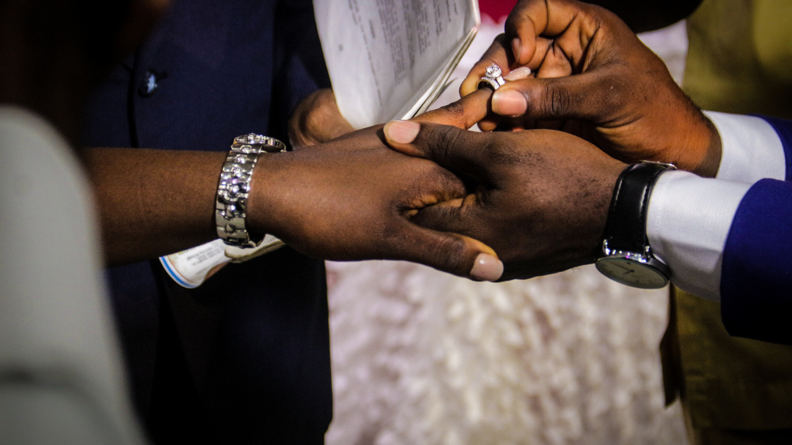 Man inserting a ring into di finger of im wife.