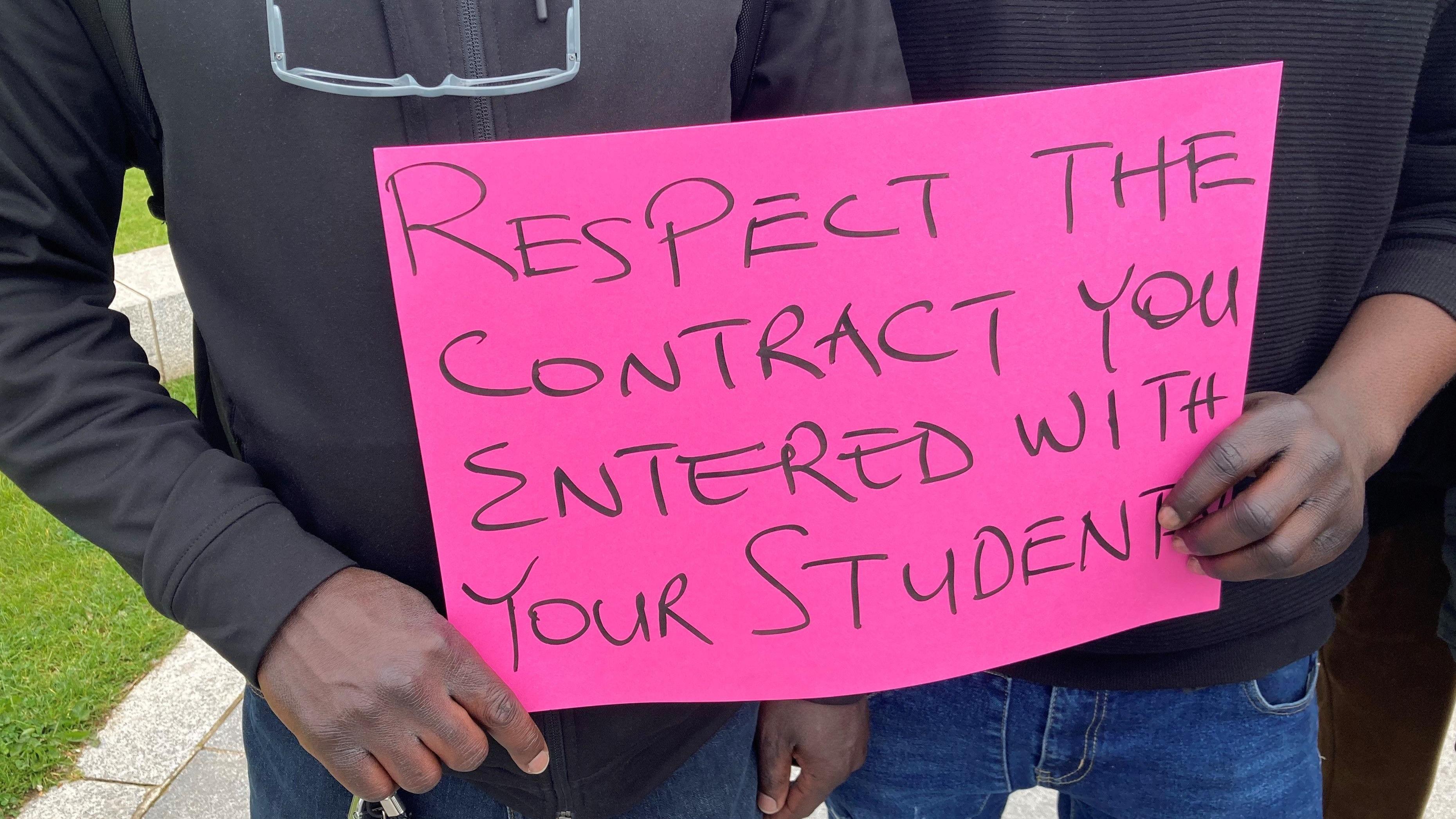 Students hold pink protest sign