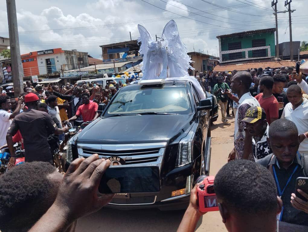 Crowd gather dey watch vehicles wey dey pass during di burial of late Mr Ibu