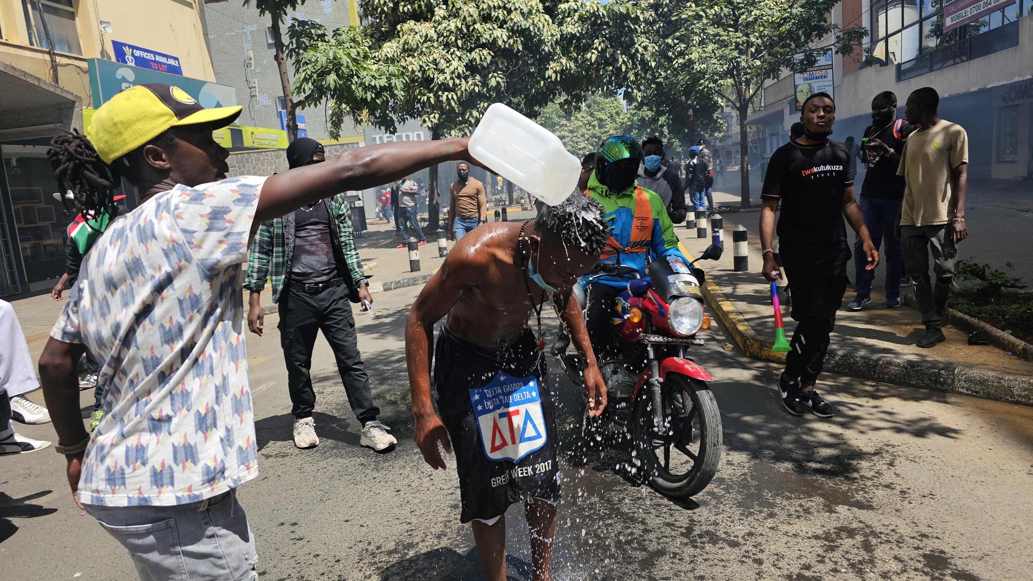 One protester pour water for im mate head for di Kenya waka against tax increase