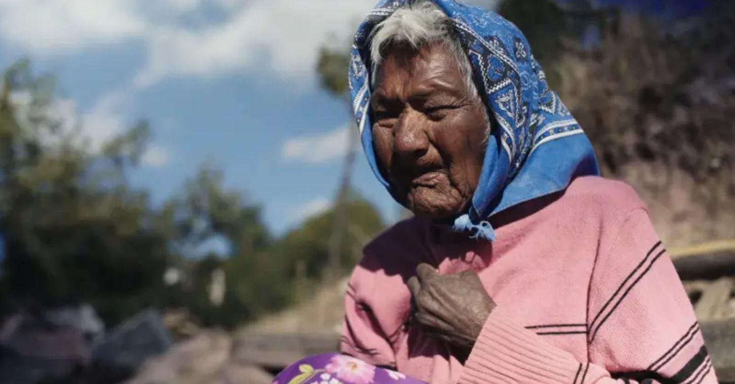 Rita Patino in her native village looking frail and very old. She has also overed her head with a blue scraf.