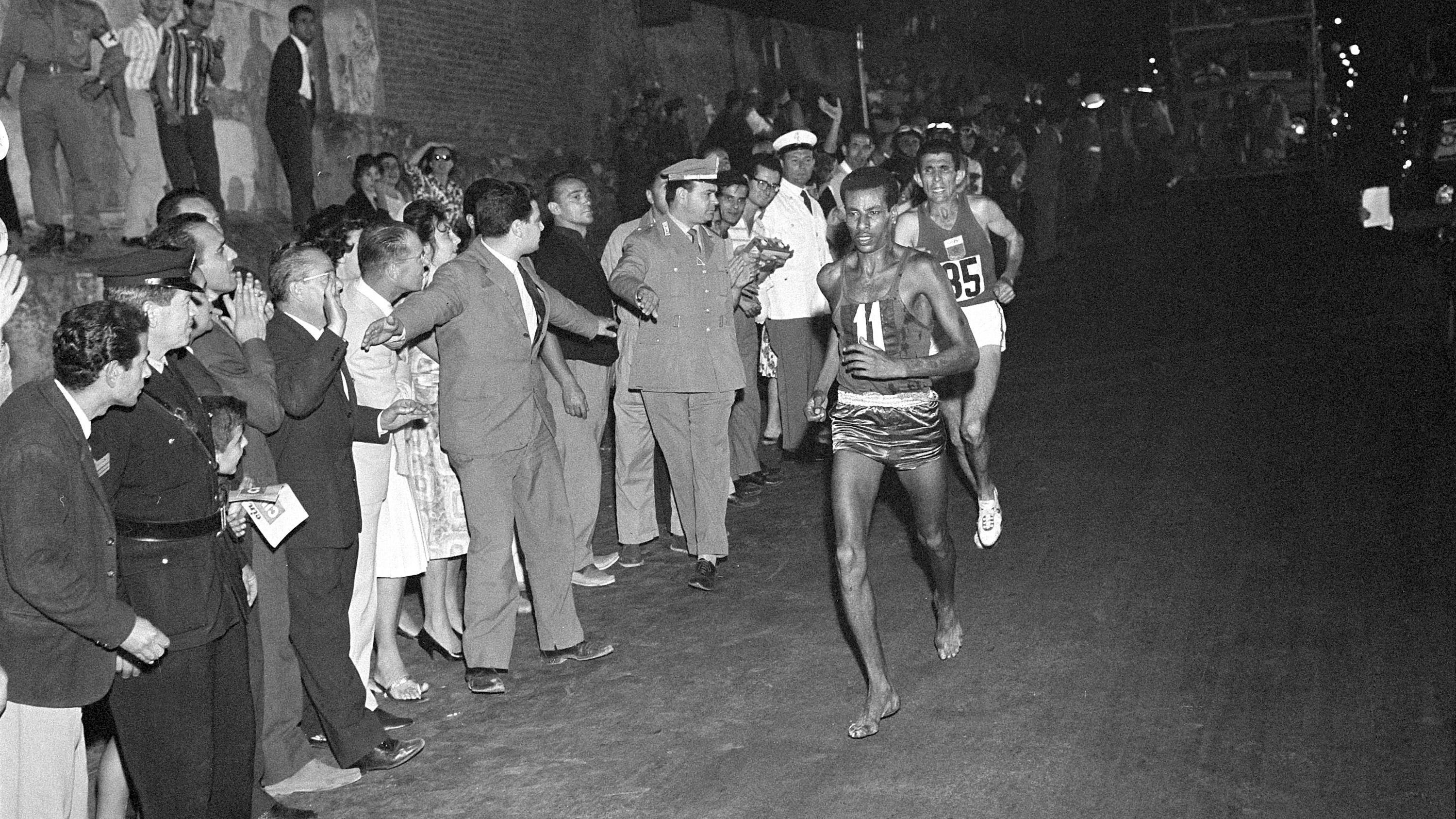 Abebe Bikila dey run marathon wit out shoe as spectators dey look