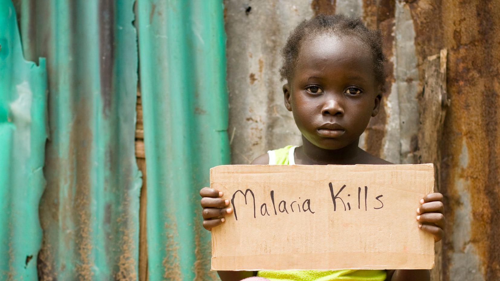 Child holding a sign that reads "malaria kills"