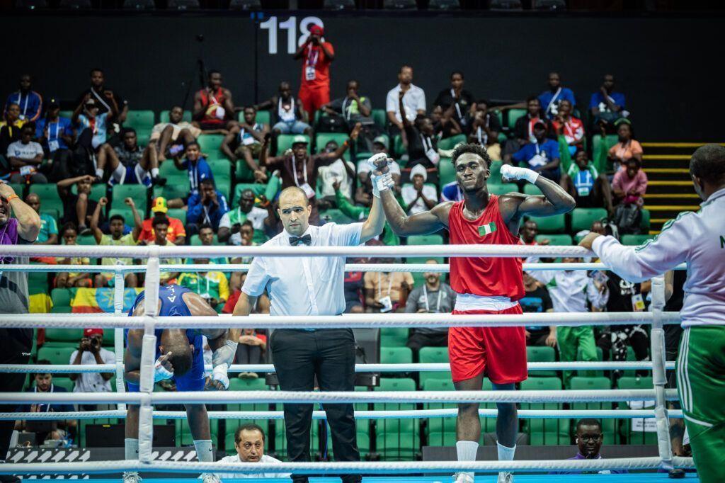 Adam Olaore wear red kit with Nigerian flag on im chest with im hand raised by di referee as e win di 2023 African Championship