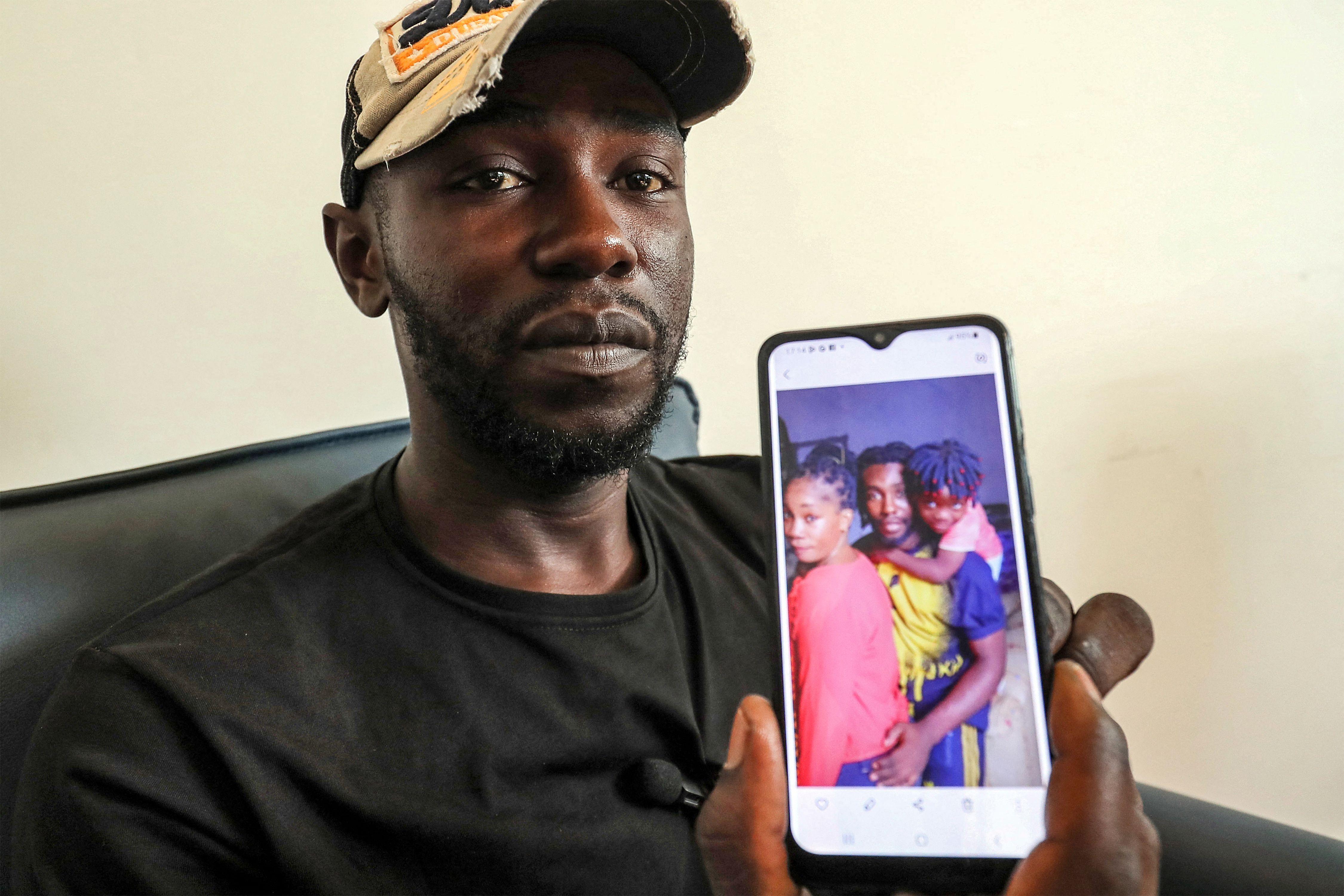 Mbengue Nyimbilo Crepin, also known as Pato, holds a photo of his wife and daughter