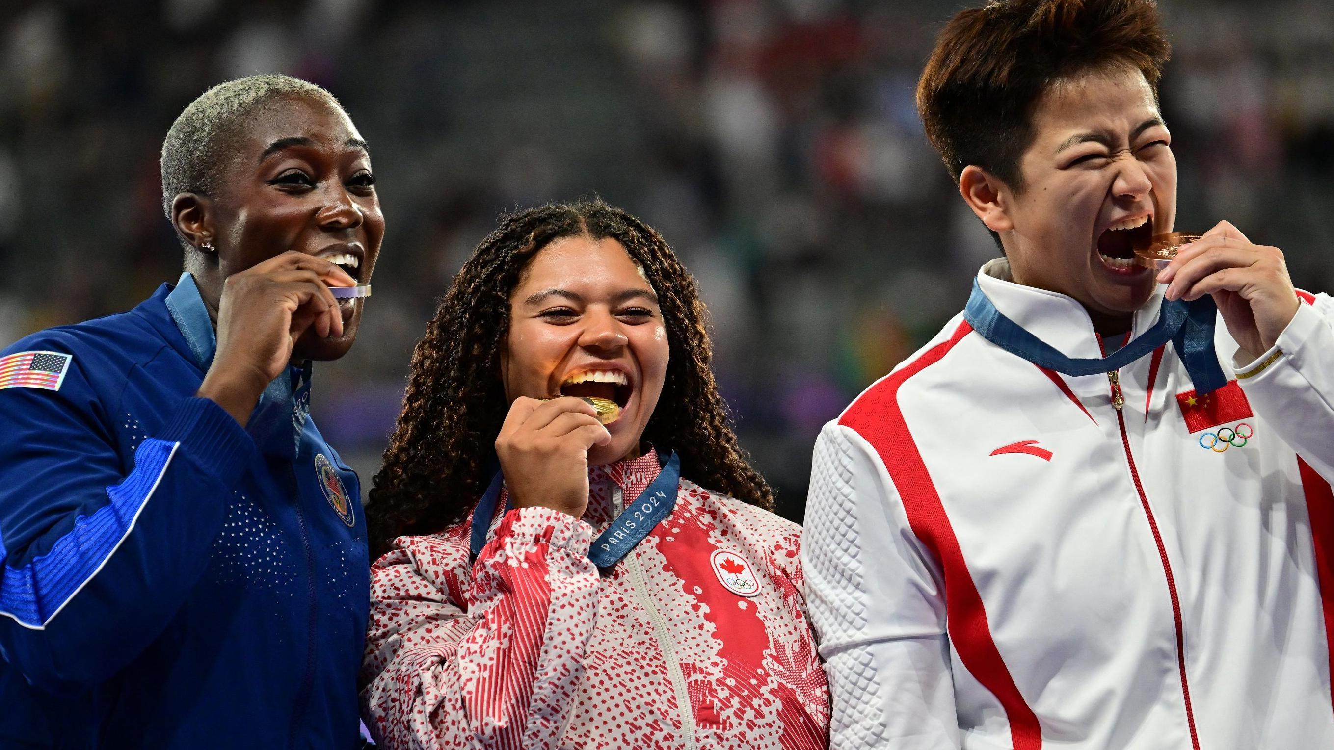 USA's Annette Echikunwoke (L), gold medallist Canada's Camryn Rogers (C) and bronze medallist China's Zhao Jie pose as they celebrate on the podium during the victory ceremony for the women's hammer throw athletics event during the Paris 2024 Olympic Games