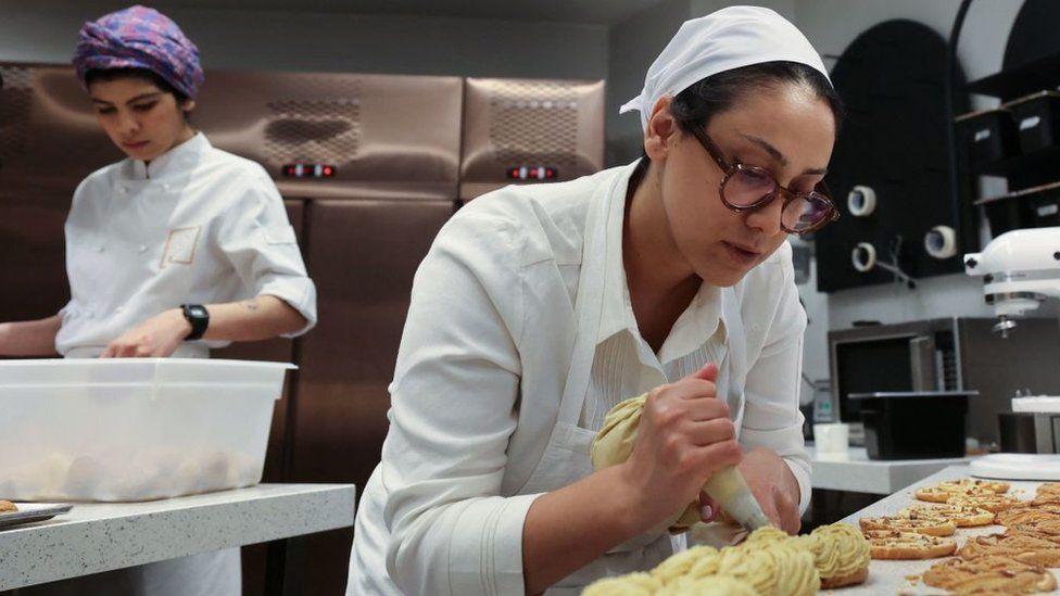 Iranian pastry chef Shahrzad Shokouhivand (R), works in the kitchen of her luxury pastry company for Tehran