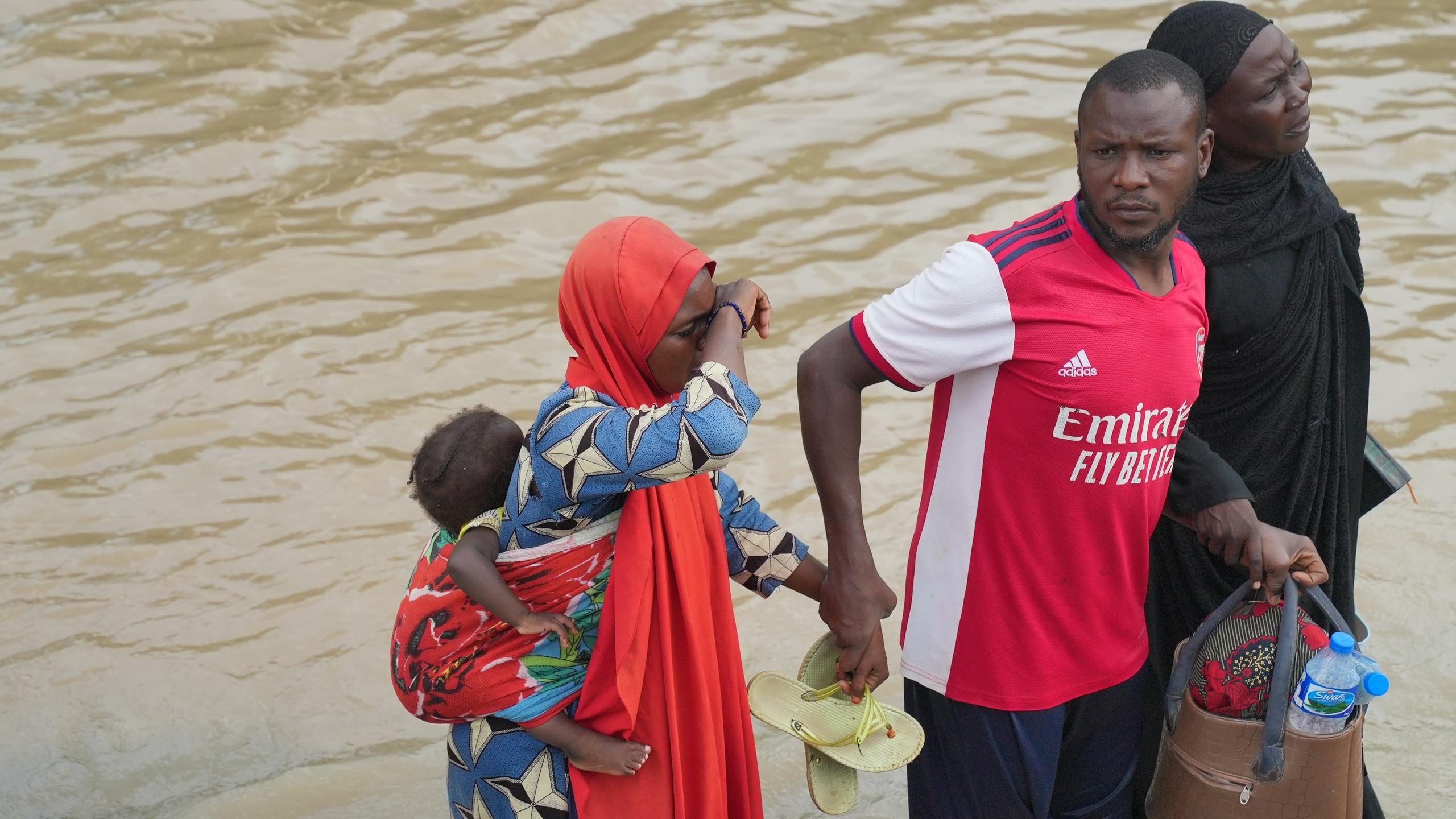 A man leads two women to safety from di flood waters