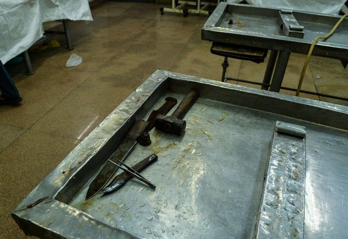  A rusted carving knife and a mallet lie on a steel table