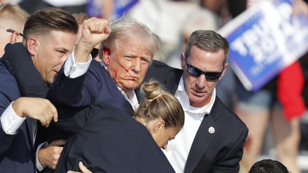 Donald Trump pumps his fist afta being grazed in the ear when a gunman fired shots during his rally