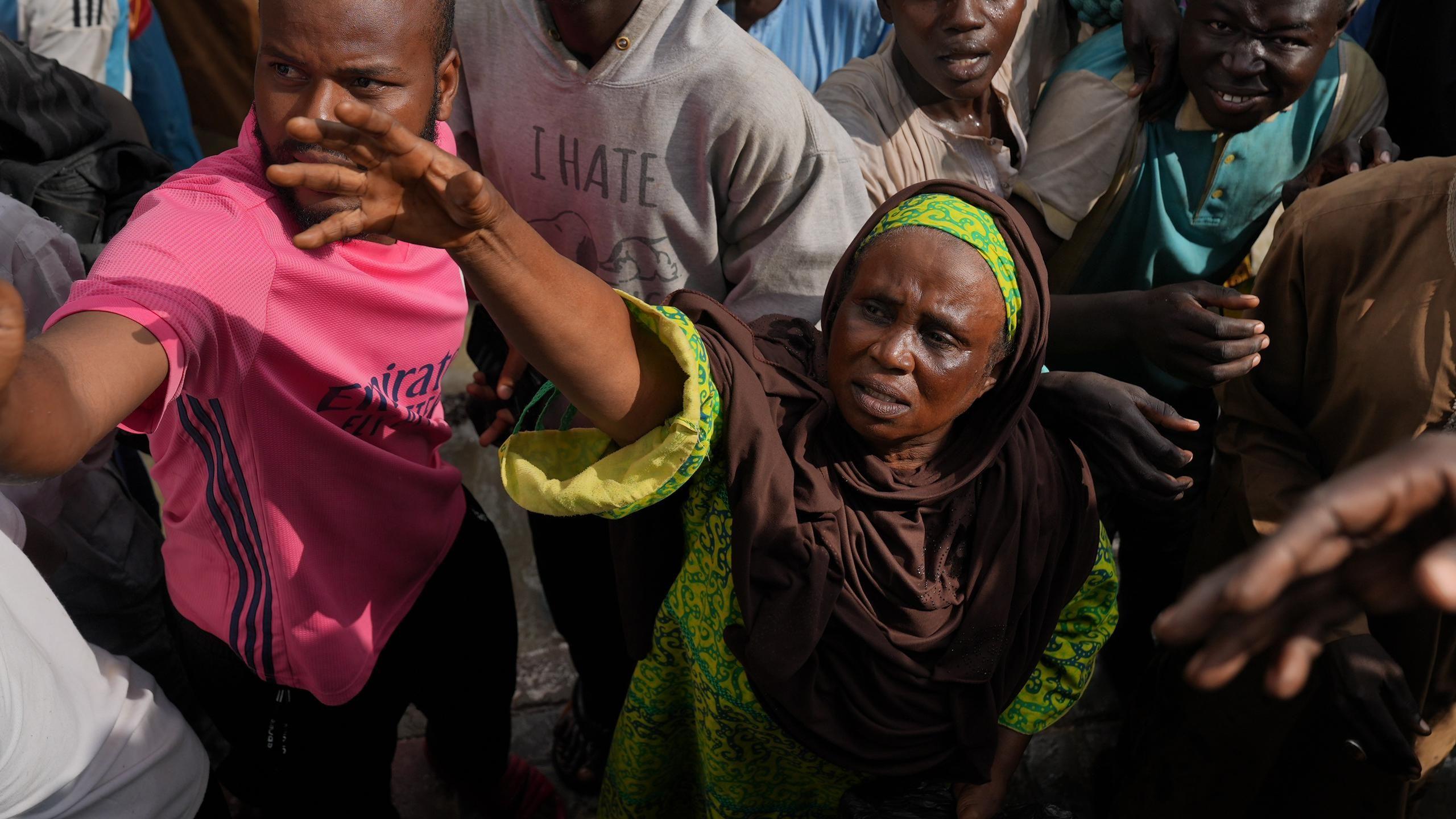 Woman stretches hand towards a food relief truck in Maiduguri