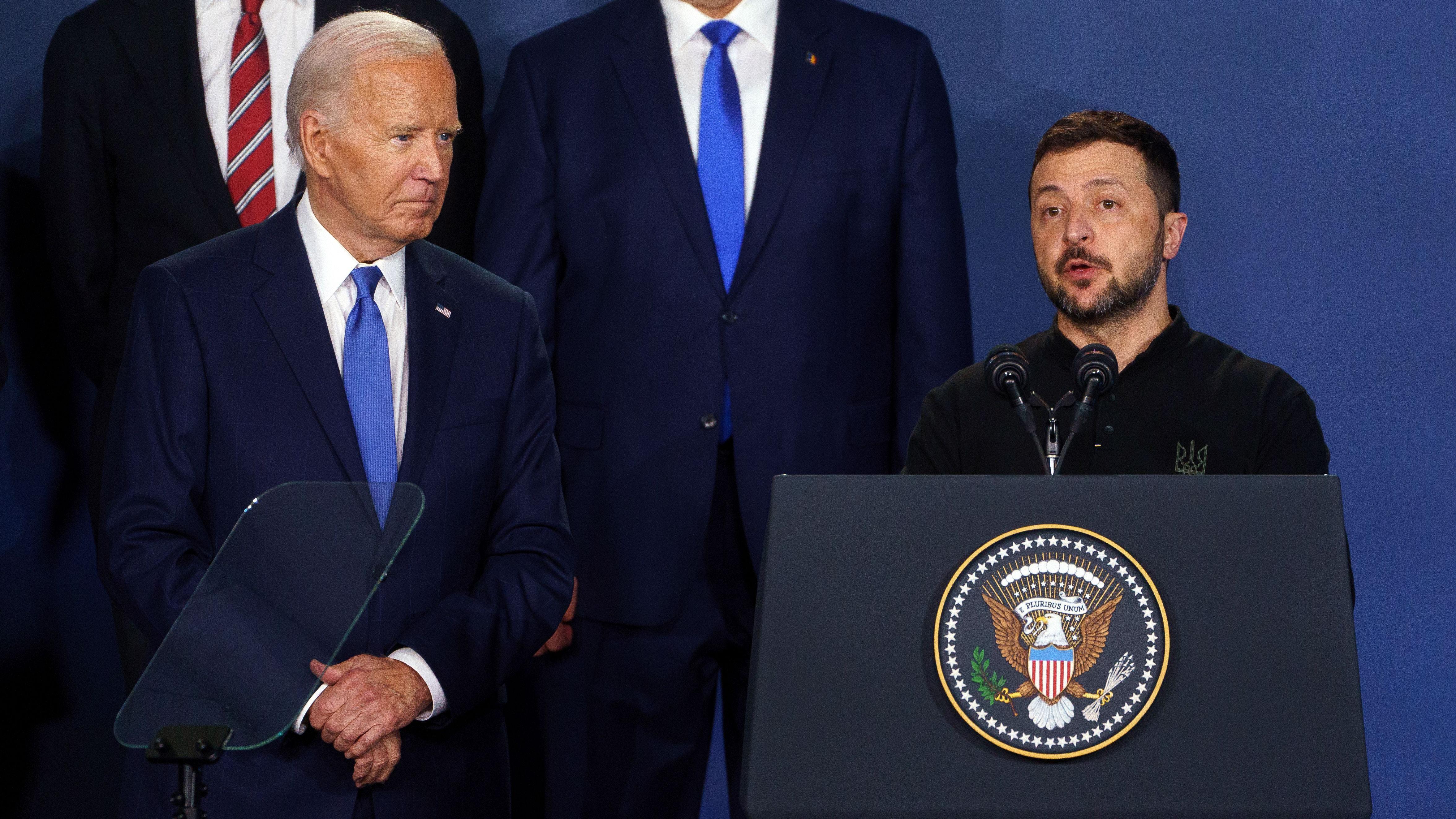 Wearing one blue tie and navy suit, US President Joe Biden stand next to Ukrainian President Volodymyr Zelensky wey dey tok from one podium addressing di Nato Summit for Washington for July 2024