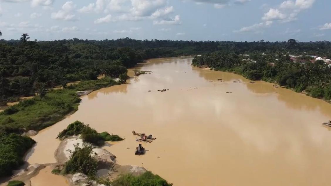 Overhead view of one of Ghana rivers wey now don turn                                                                                                                           dark brown due to heavy pollution by illegal mining activities