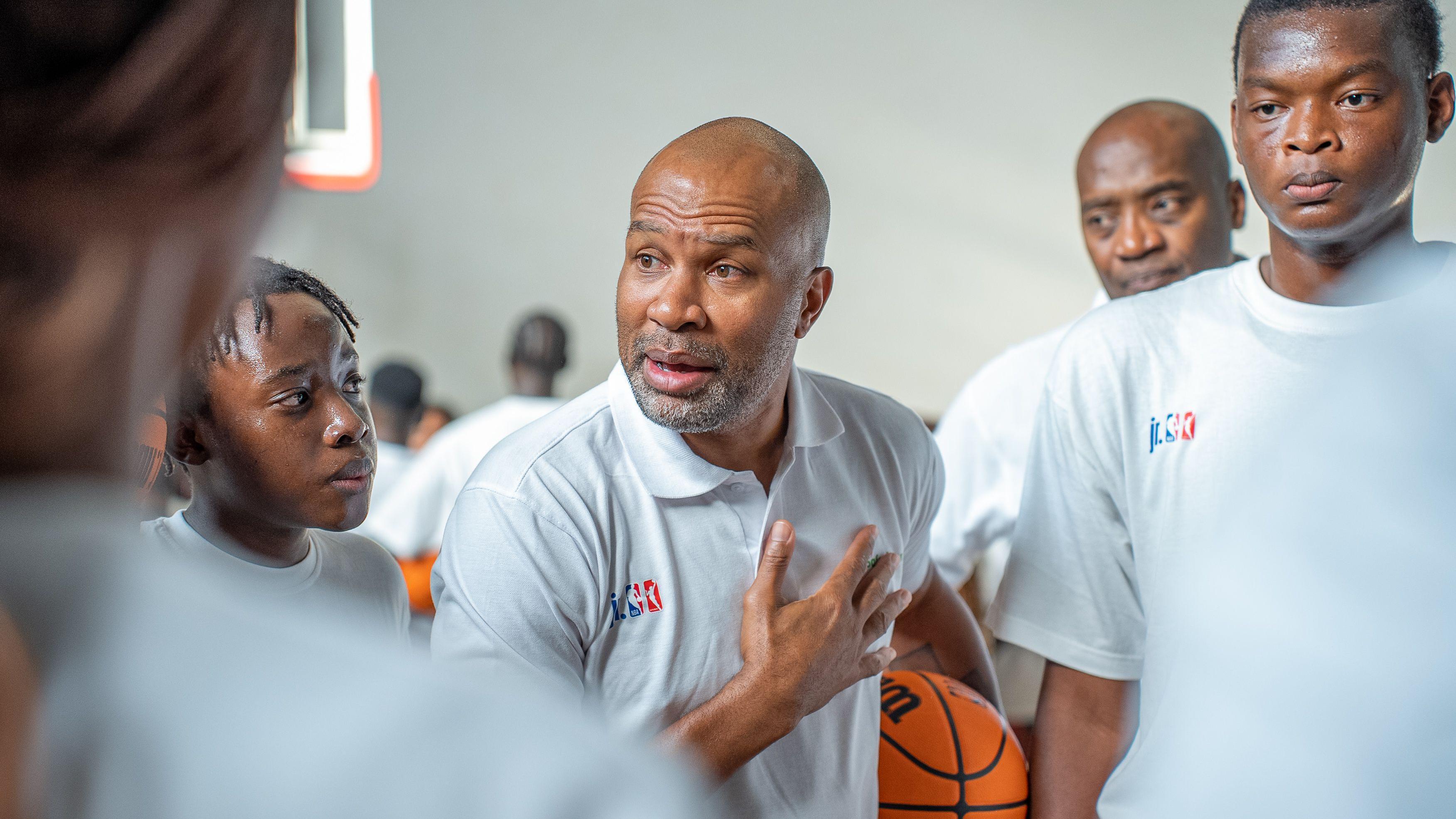 Derek Fisher (centre) holds a basketball under his arm while giving a talk to youngsters during a training session in Kenya