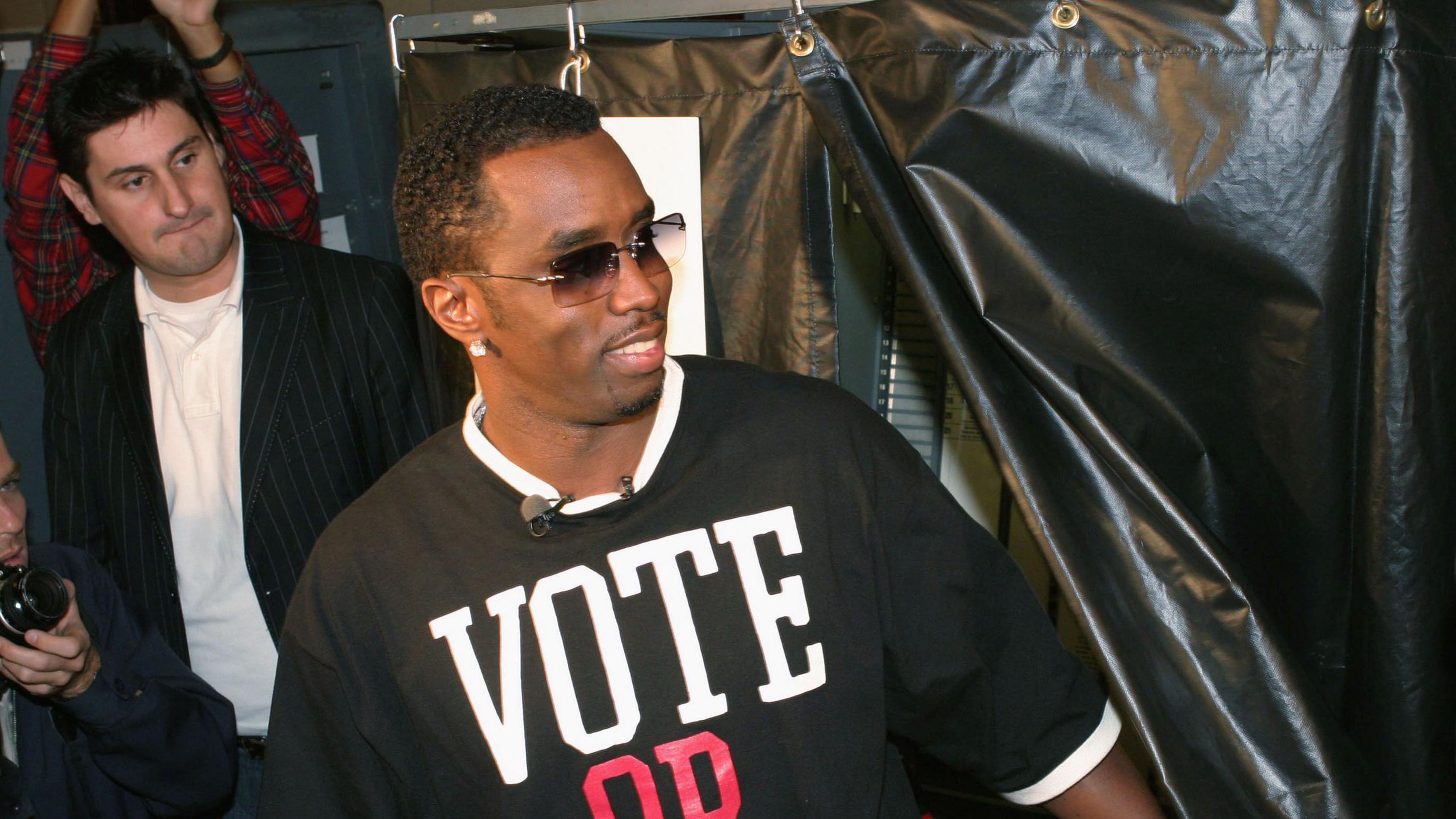 Sean "Diddy" Combs wit a voting T-shirt for one event for 2004. Im publicist Rob Shuter dey di background. 