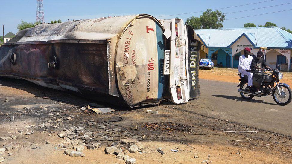 Two people dey on motorbike and dey ride along di road wia one tanker fall for Majia, Jigawa, Nigeria - 16 October 2024
