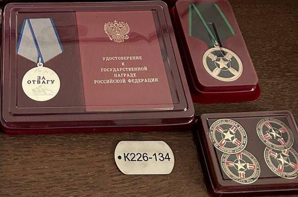 A dog tag inscribed with "K226-134" and a medal engraved with the words "for bravery" 