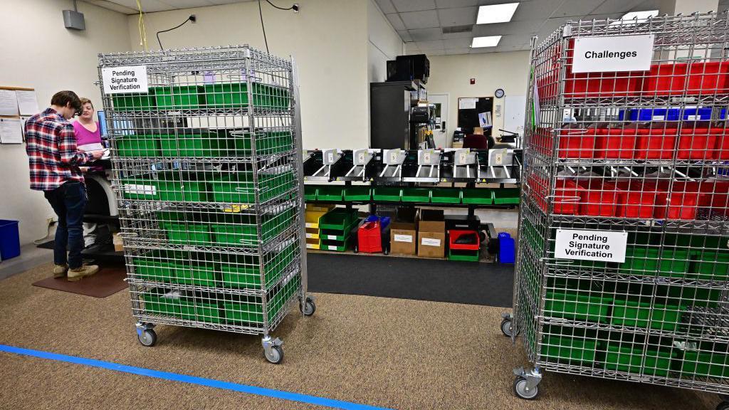 Trays of ballots wey don dey challenged or require signature verification for a ballot processing site for California