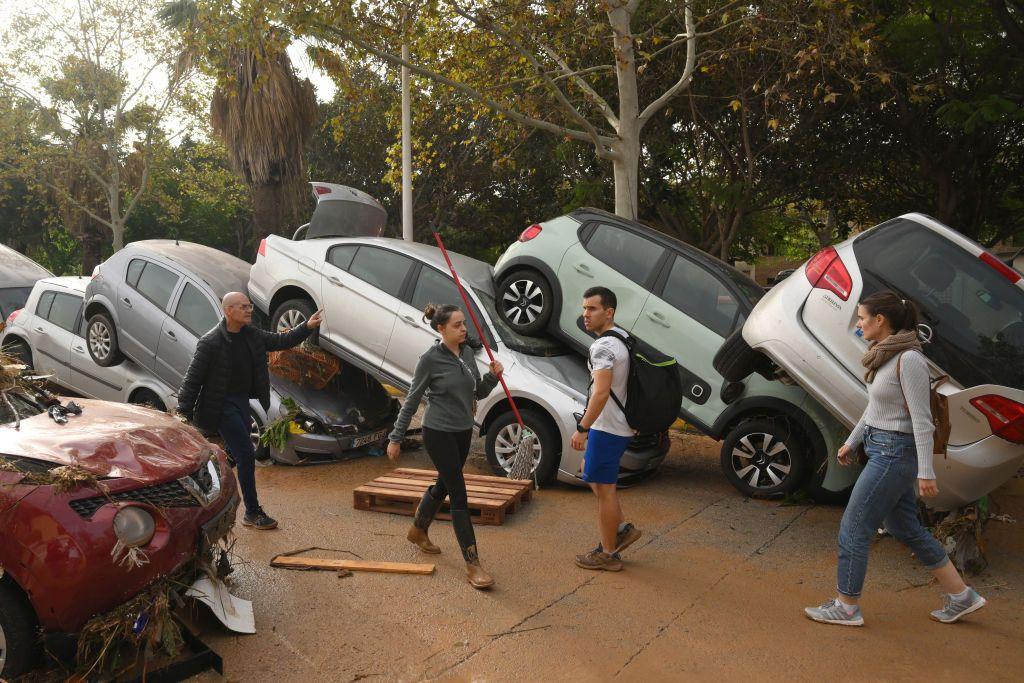 Cars piled up in a line as people walk past them 